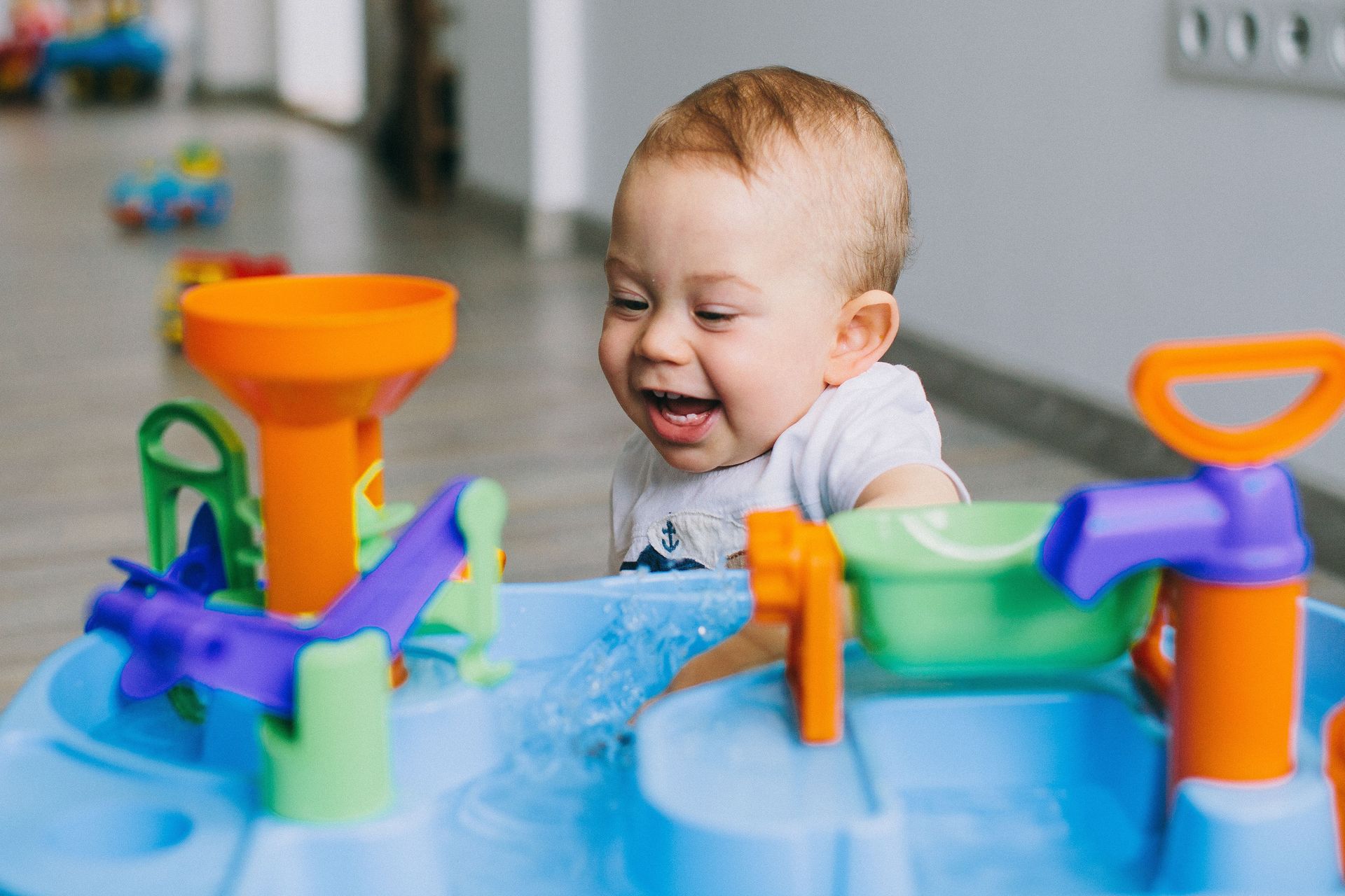 A happy baby enjoying playtime with a colorful water toy indoors.